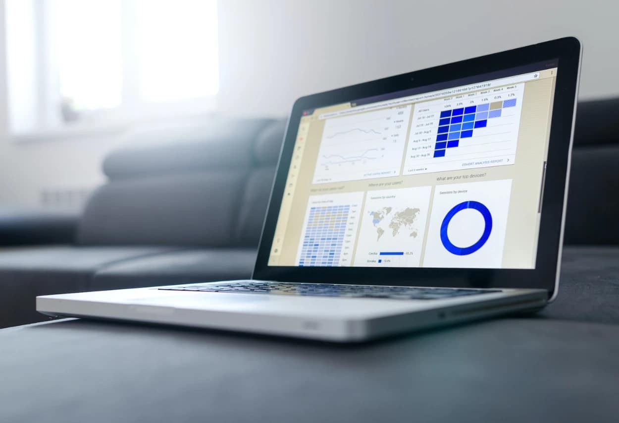 Laptop screen showing SEO performance analysis dashboard with traffic growth graphs and user demographic data.