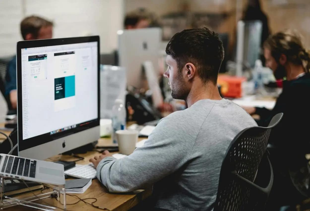 SEO specialist analyzing SEO timeline and results on a computer in a bustling office setting.