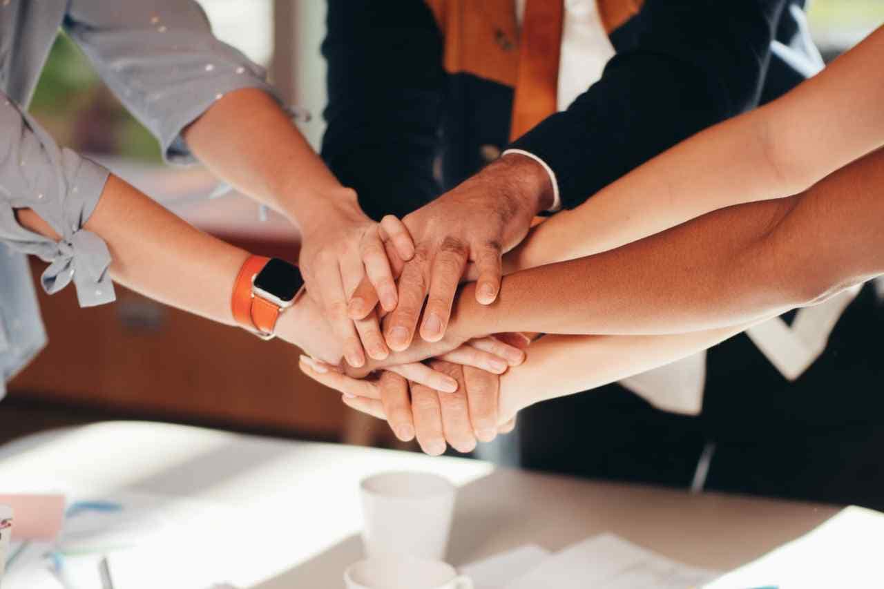 A diverse team places their hands together in a stack, signifying collaboration and commitment to sustainable practices in digital marketing.