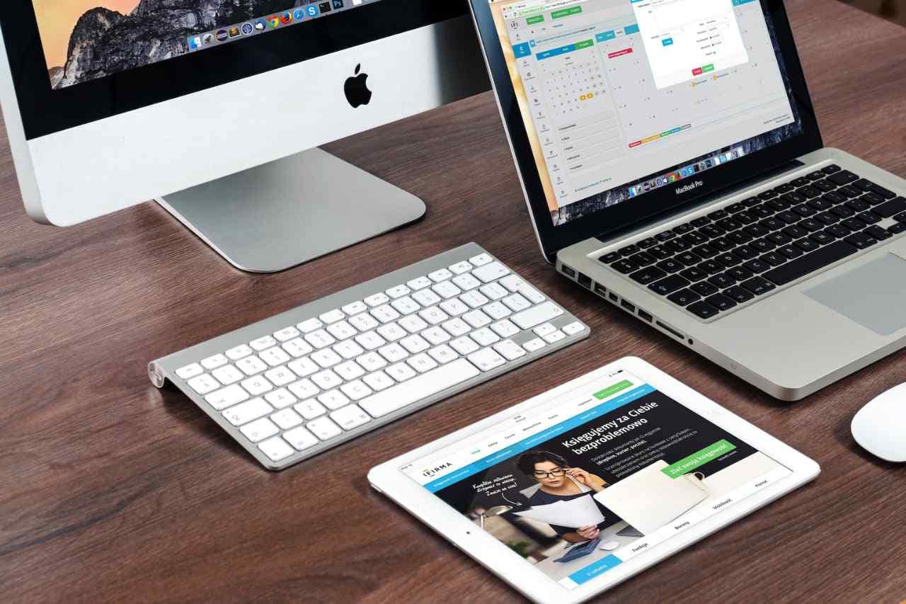 A professional workspace showcasing an iMac, MacBook, and iPad with marketing analytics on screen, exemplifying the use of digital tools in sustainable marketing strategies.