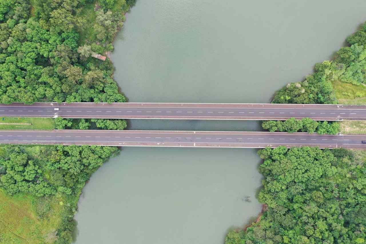 Aerial view of a bridge over a tranquil river, flanked by dense green foliage, representing the integration of sustainable practices in the digital marketing infrastructure.