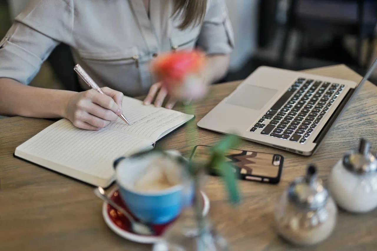 Professional content optimization strategist planning SEO tactics with notebook and laptop in a modern workspace