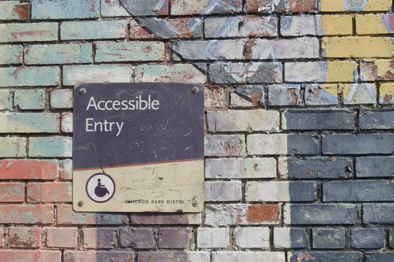 Accessible entry sign on a colorful brick wall, symbolizing commitment to physical and web accessibility