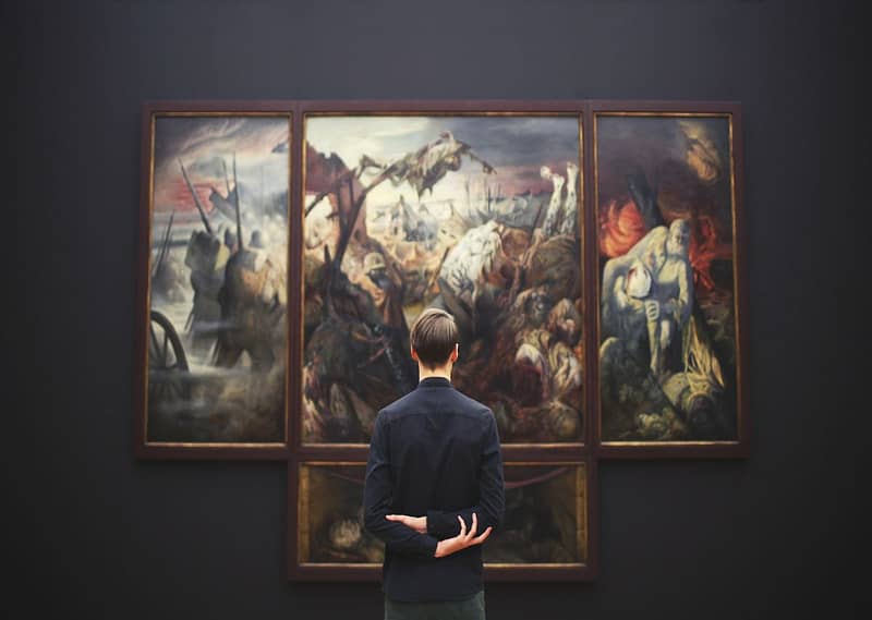 Visitor standing in front of a huge renaissance masterpiece in a museum
